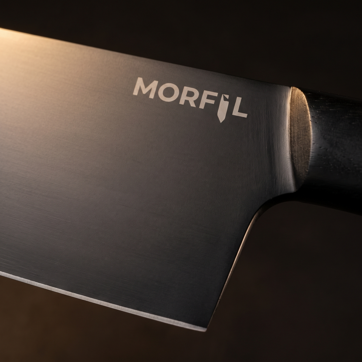 Gros plan sur la lame noire lisse du couteau Charbon et le logo Morfil gravé près du talon