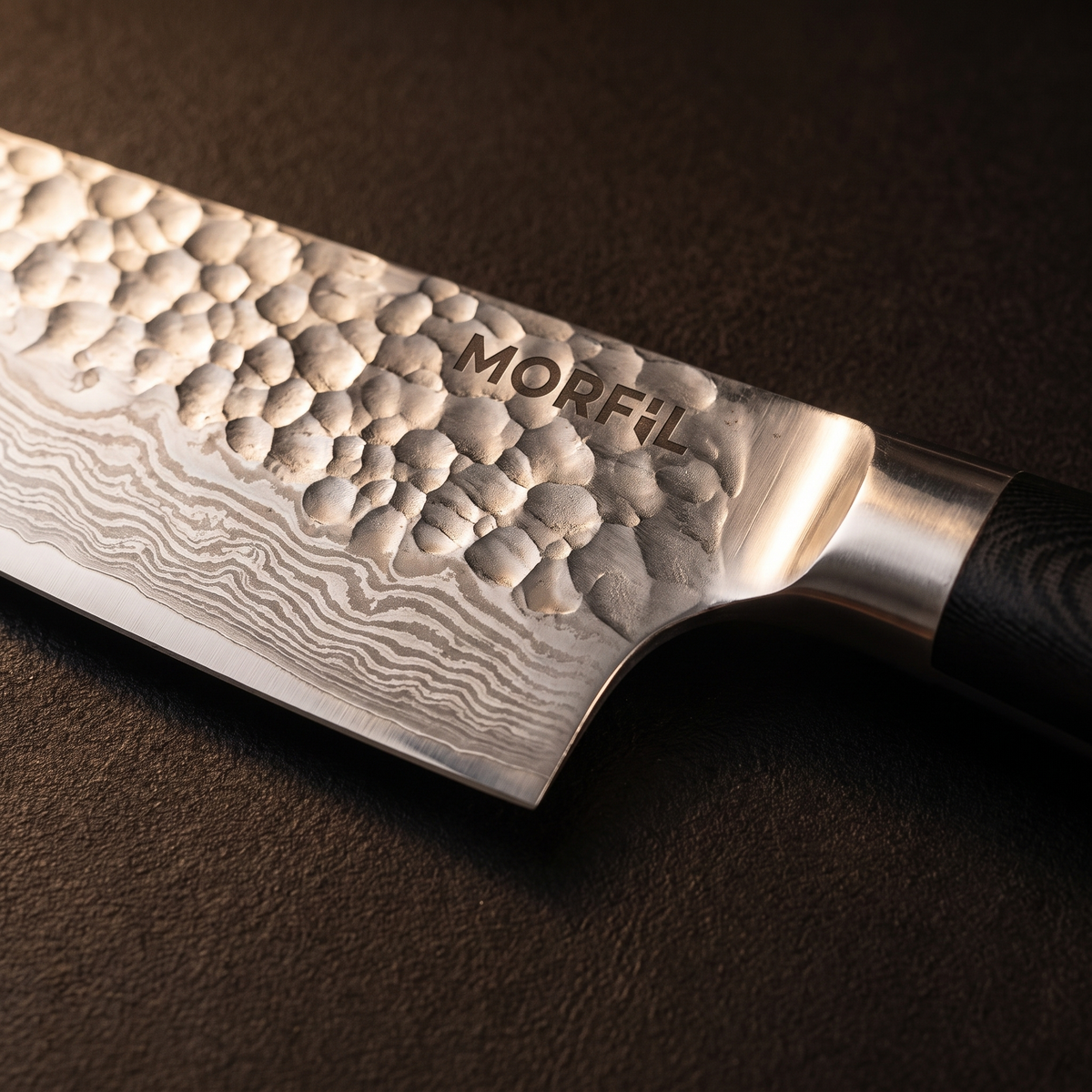 Gros plan sur la lame d'Étincelle : martelage en haut, motif ondulé en bas, mitre inox et logo Morfil gravé