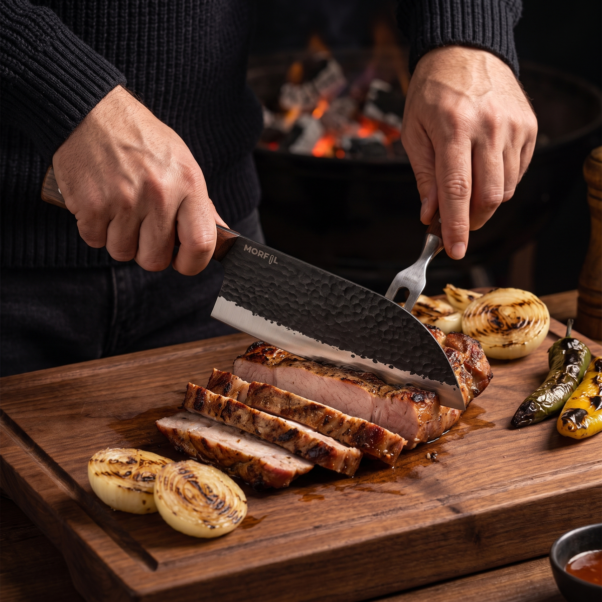 Mains tranchant une échine de porc grillée avec le couteau Fournaise, braises en arrière-plan