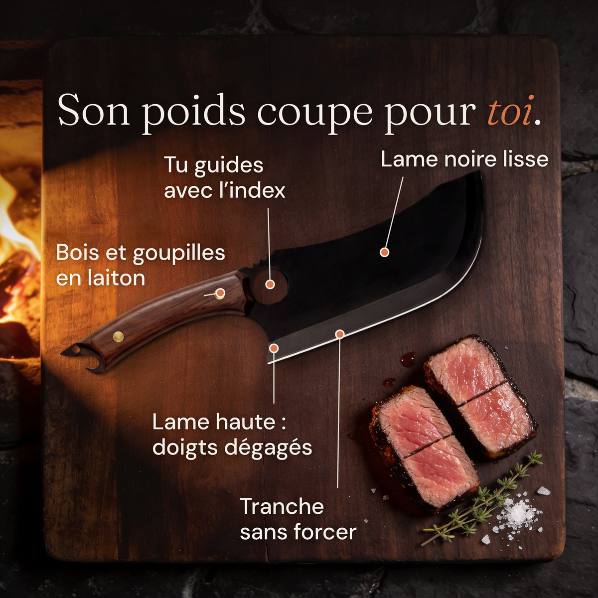 Charbon sur une planche sombre près du feu, à côté de deux portions épaisses de côte de bœuf, avec ses atouts : lame noire lisse, trou pour guider avec l’index, bois et goupilles en laiton, lame haute qui dégage les doigts, tranche sans forcer.